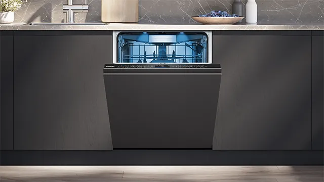Siemens fully integrated built-in dishwasher open in a dark kitchen